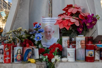 A makeshift shrine with devotional candles, flowers, and images of Pope Francis appears outside Rome's Gemelli hospital on Feb. 22, 2025